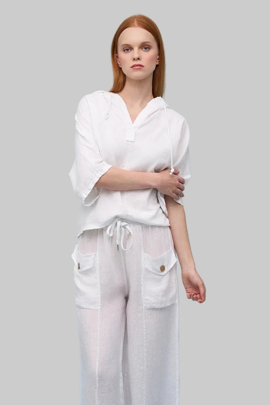 Woman wearing a white outfit with wide-leg pants on a light blue background