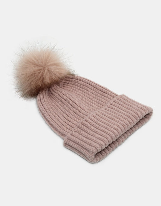 Knitted beanie with a fur pom-pom on a light gray background