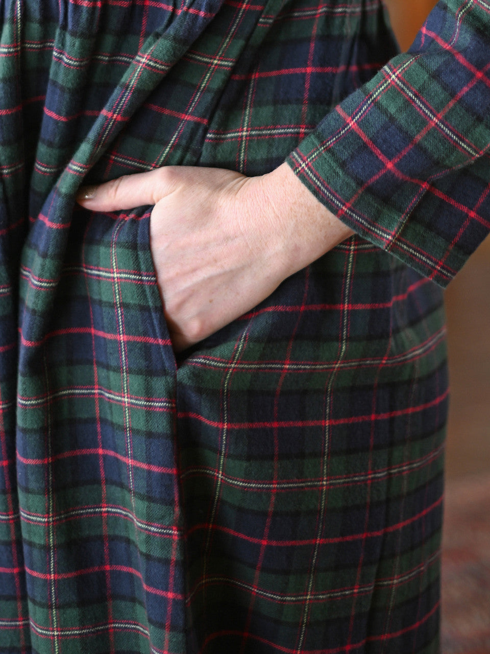 Close-up of a person wearing a plaid robe with a hand in the pocket.