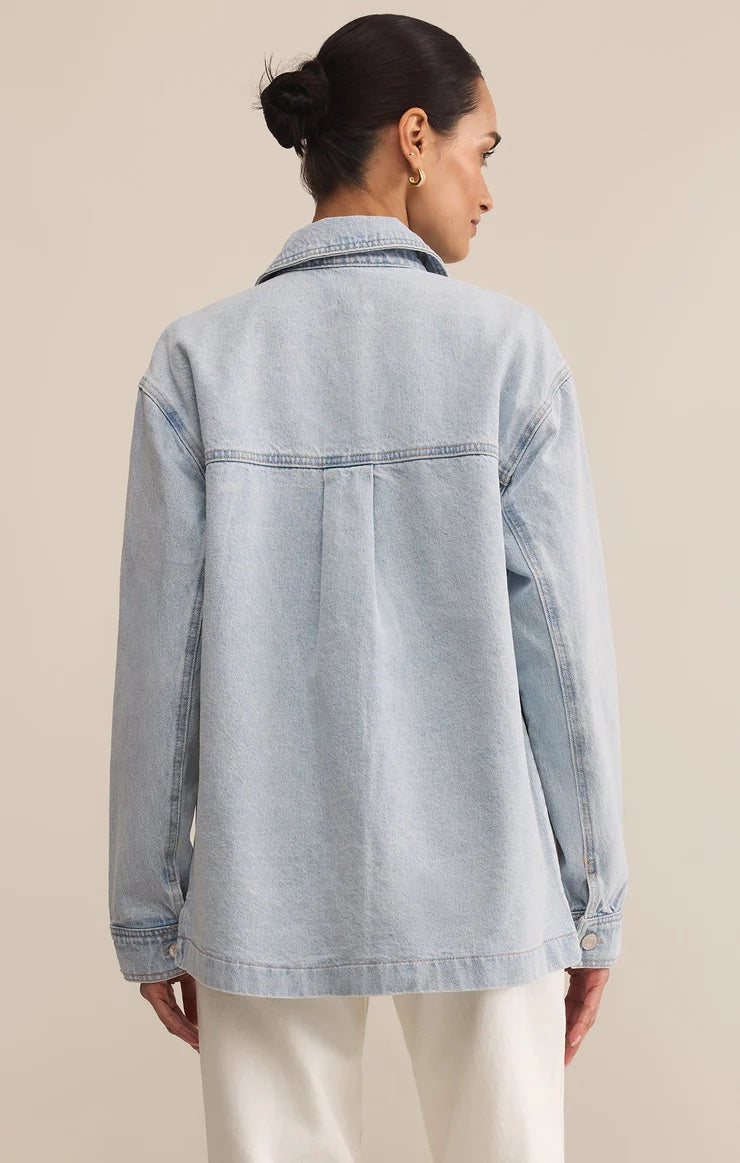 Woman wearing a light blue denim jacket on a beige background | Z Supply On The Road Denim Jacket | Faded Indigo, Designed in USA