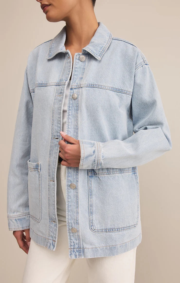 Light blue denim jacket worn by a person on a beige background | Z Supply On The Road Denim Jacket | Faded Indigo,