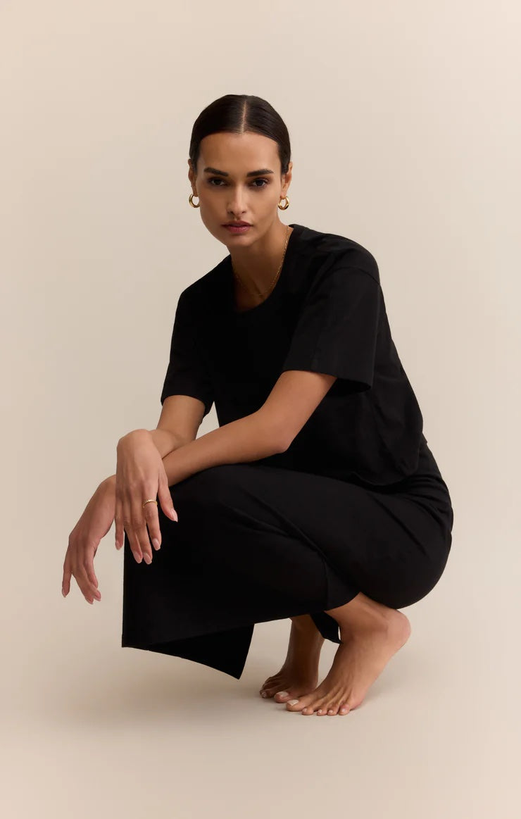 Woman wearing a black outfit sitting on a beige background | Z Supply On The Go Tee | Black