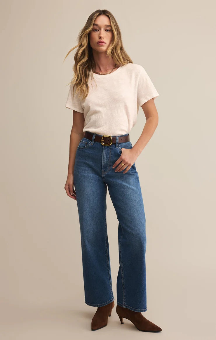 Woman wearing a white t-shirt and blue jeans against a beige background | Z Supply Foundation Slub Tee | White