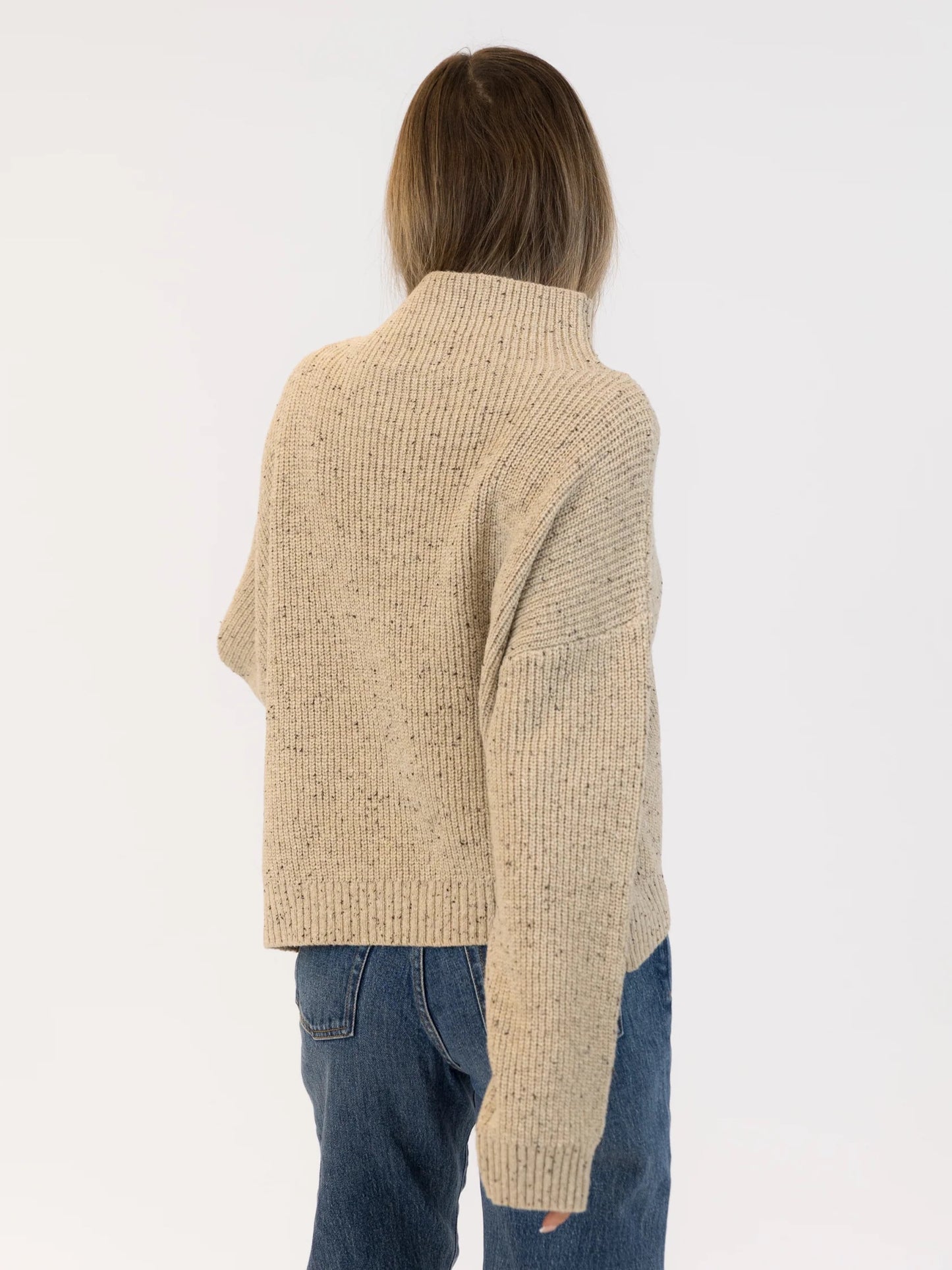 Person wearing a beige ribbed sweater and blue jeans on a white background | Lyla + Luxe Evolet Fleck Sweater | Neutral