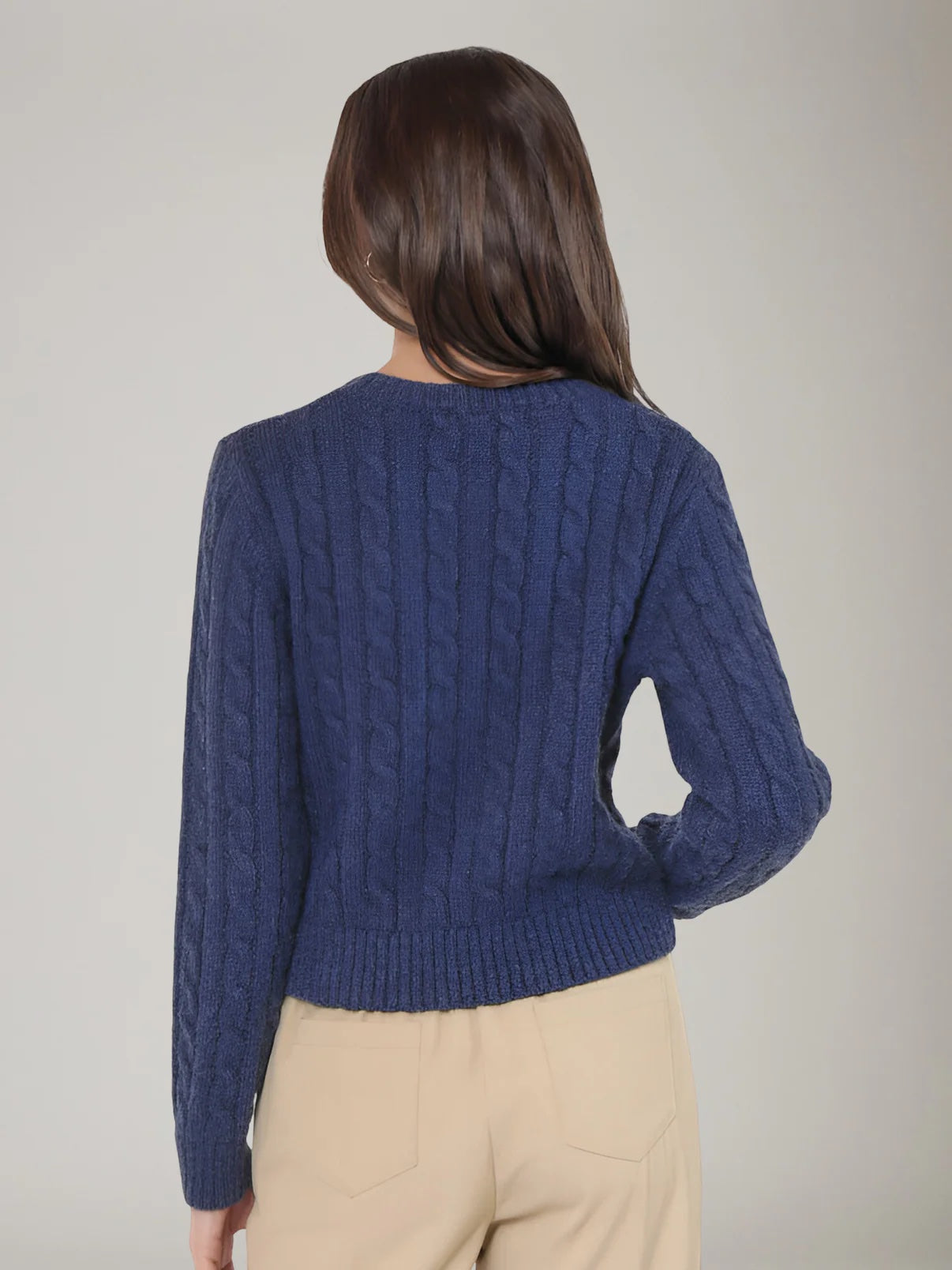 Person wearing a blue cable knit sweater against a neutral background | Sadie and Sage | Lulu Embroidered Daisy Sweater, Navy