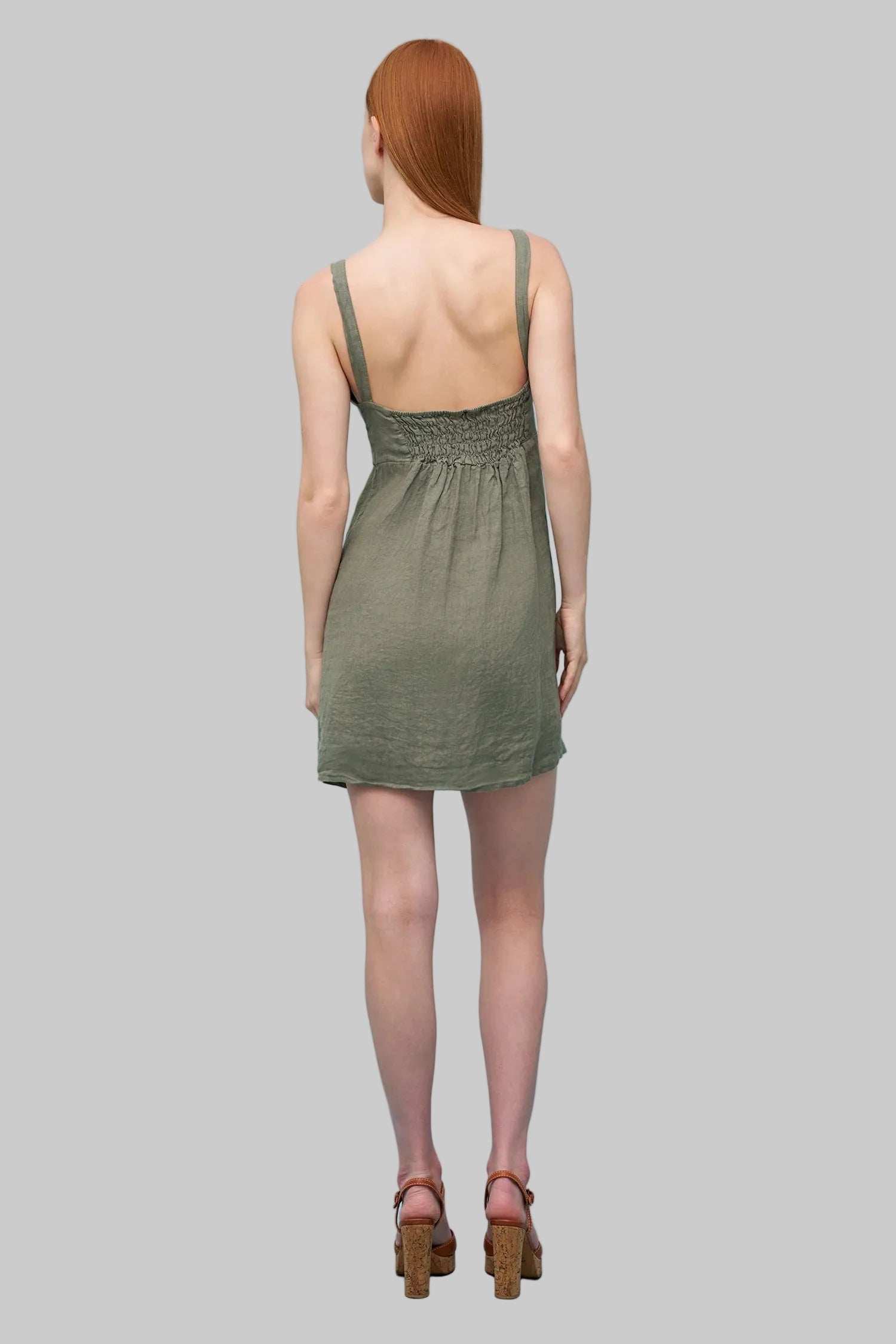 Woman wearing a green dress against a light grey background