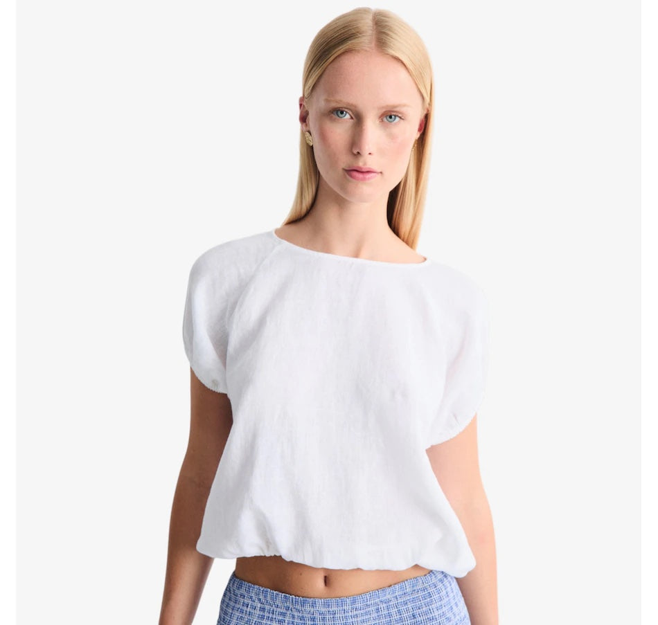 Woman wearing a white top with puffed sleeves on a plain background