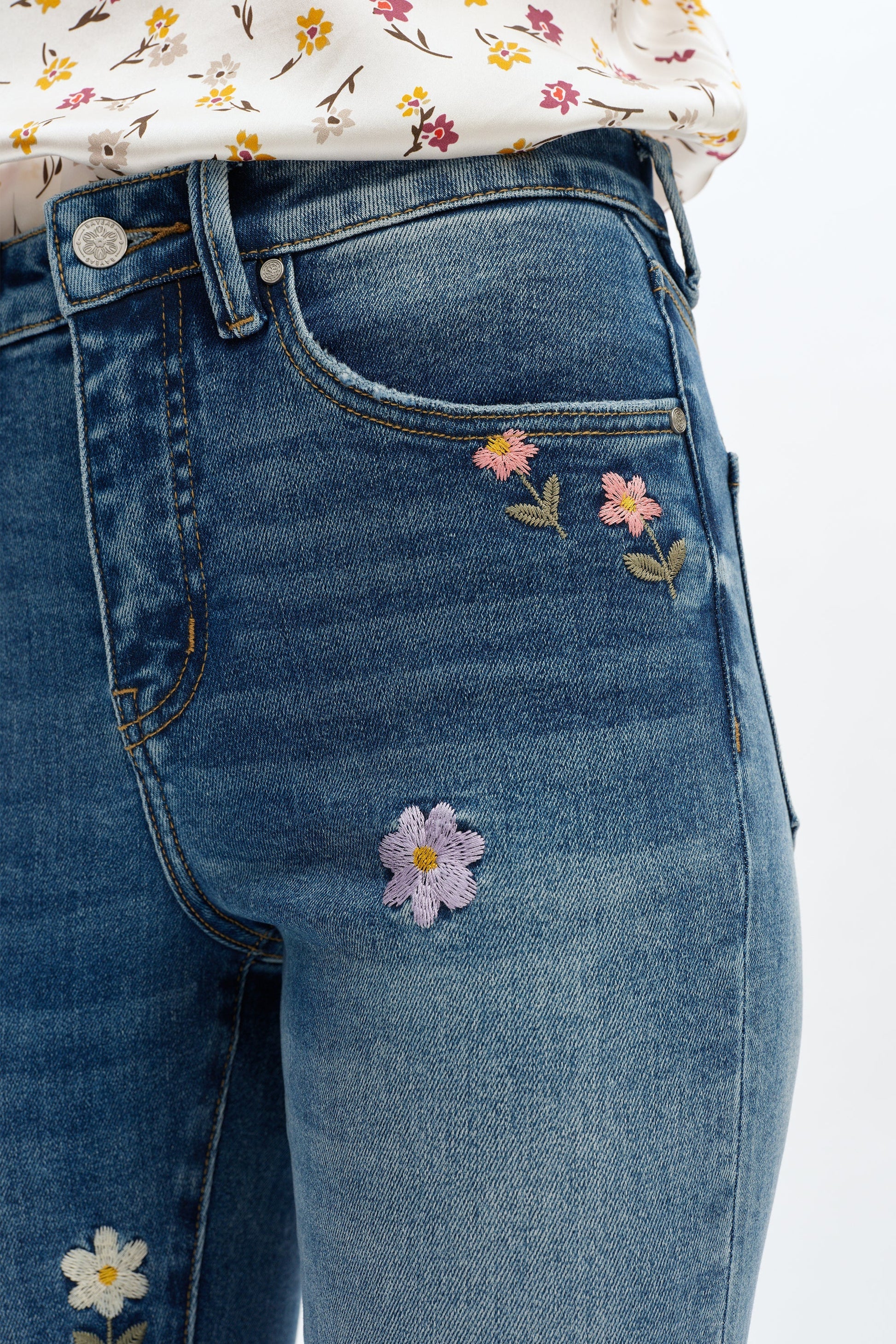 Blue jeans with floral embroidery on a white background
