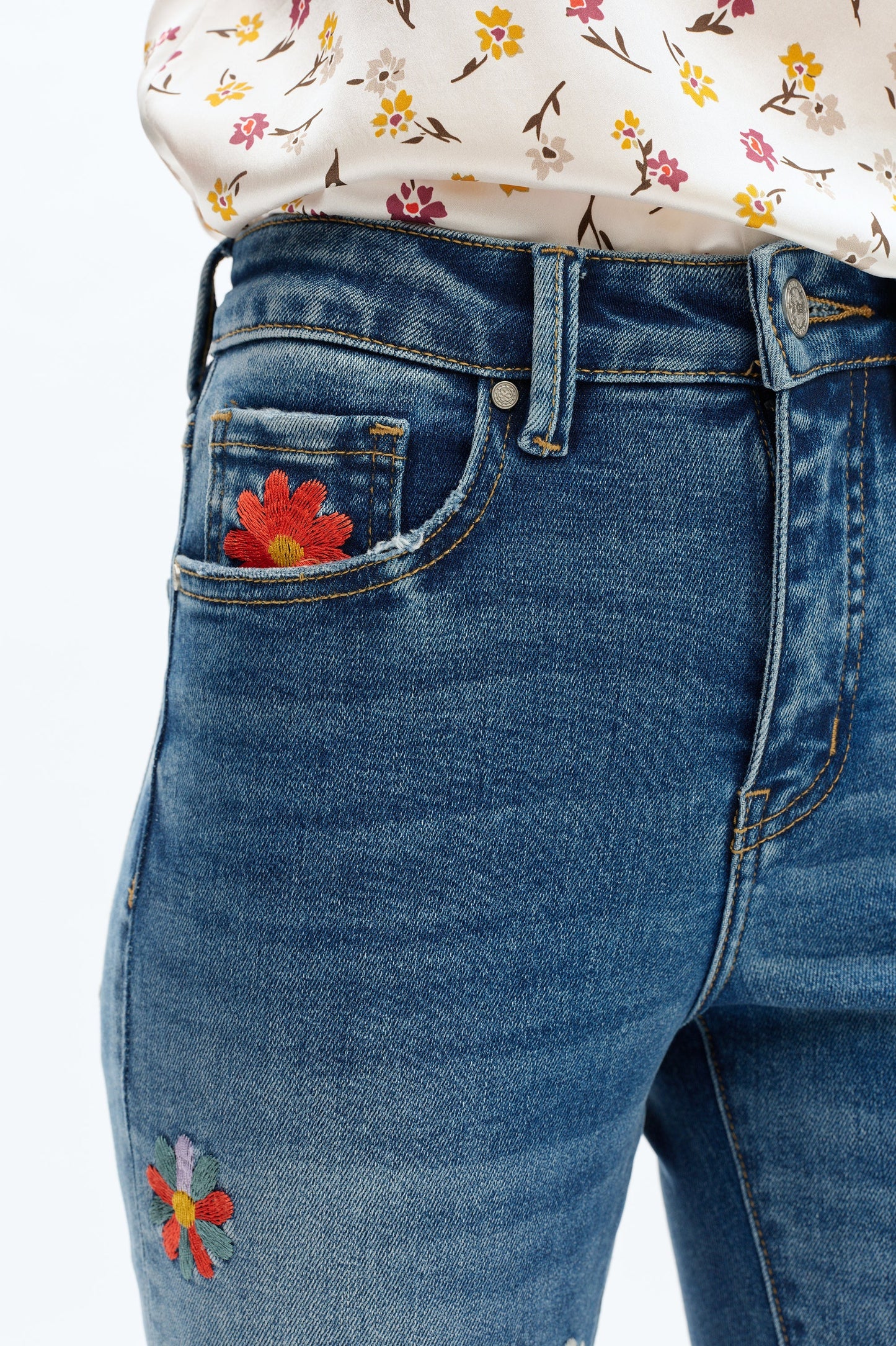 Blue jeans with floral embroidery on a white background