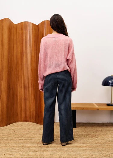 Person wearing a pink sweater and dark pinstripe pants standing in front of a wooden screen. FRNCH Lys Sweater | Pale Pink, Designed in France