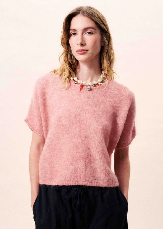Woman wearing a pink sweater against a light pink background