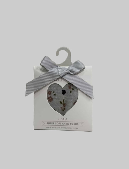 Box of super soft crew socks with a heart cutout and gray ribbon on a textured surface