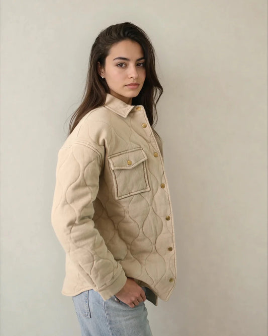 Woman wearing a beige quilted jacket against a plain background