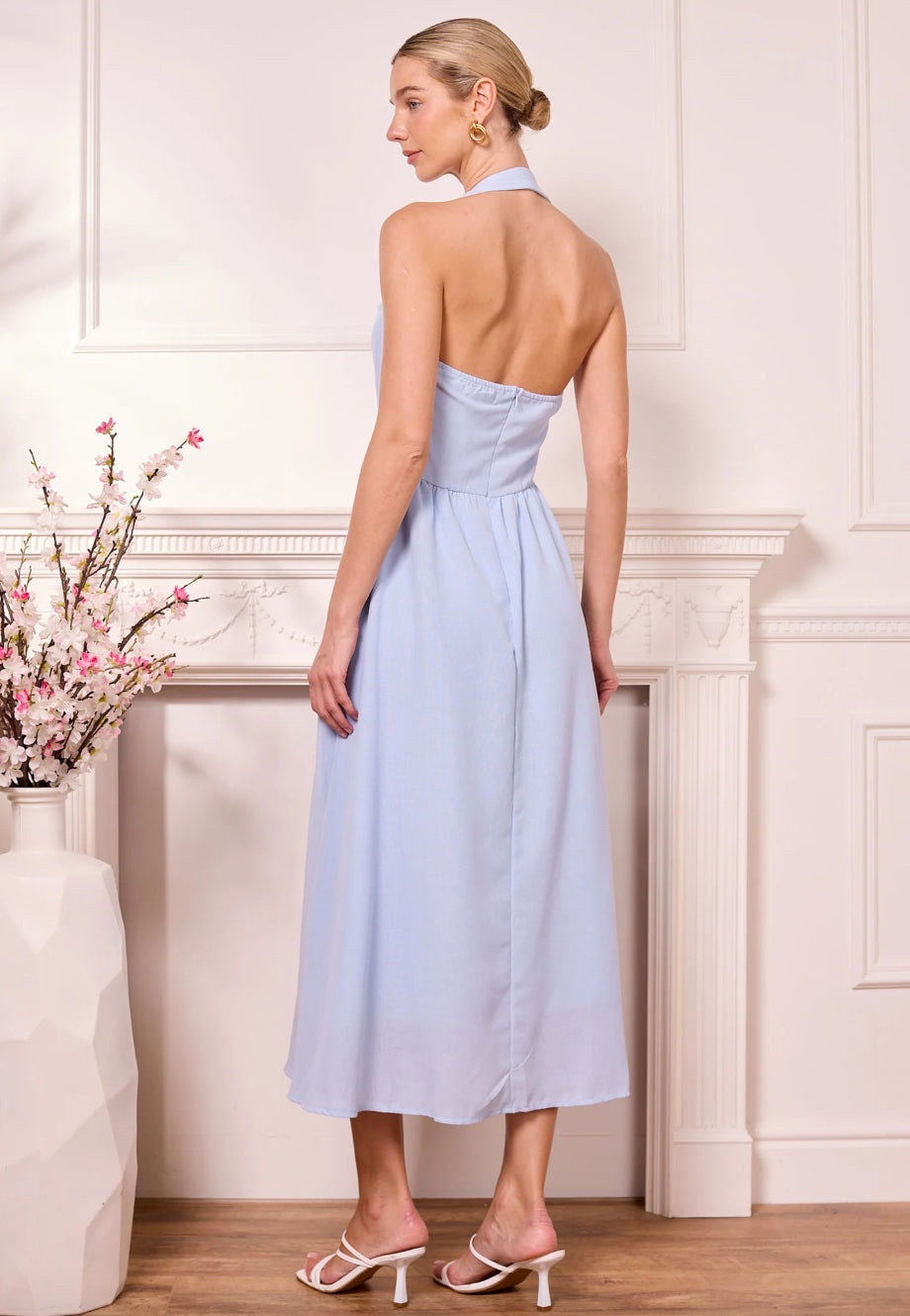 Woman in a light blue dress standing in a room with decorative elements.