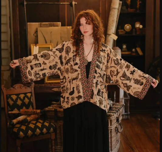 Woman wearing a patterned jacket in a room with furniture and decor.