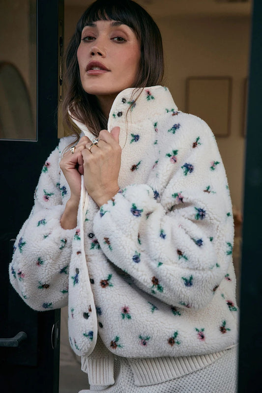 Woman wearing a white floral-patterned coat with a blurred background | Saltwater Luxe Deeda Jacket | Designed in the USA 