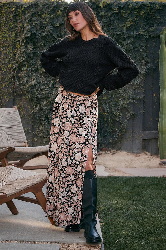 Woman wearing a black sweater and floral skirt outdoors