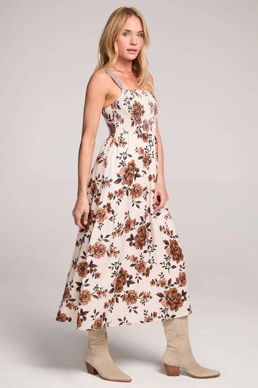 Woman wearing a floral dress with beige boots on a plain background