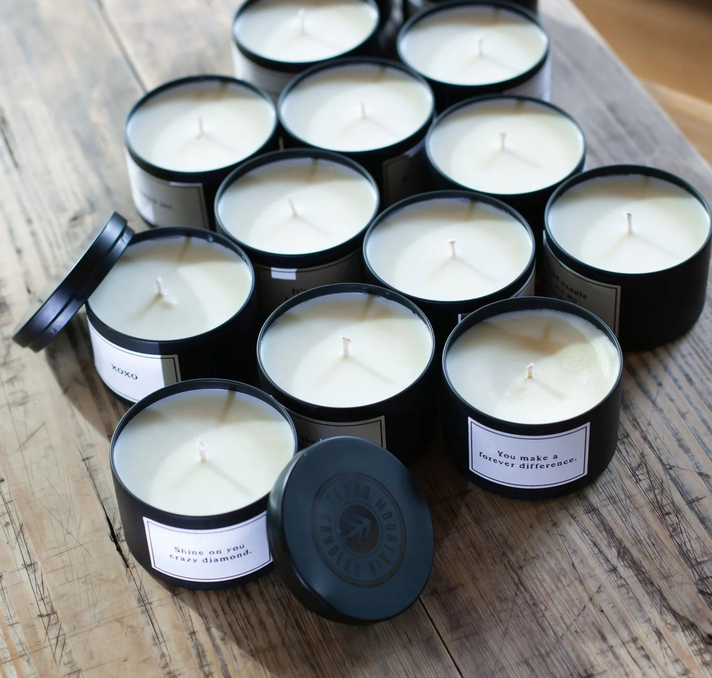 Black candles with labels on a wooden surface
