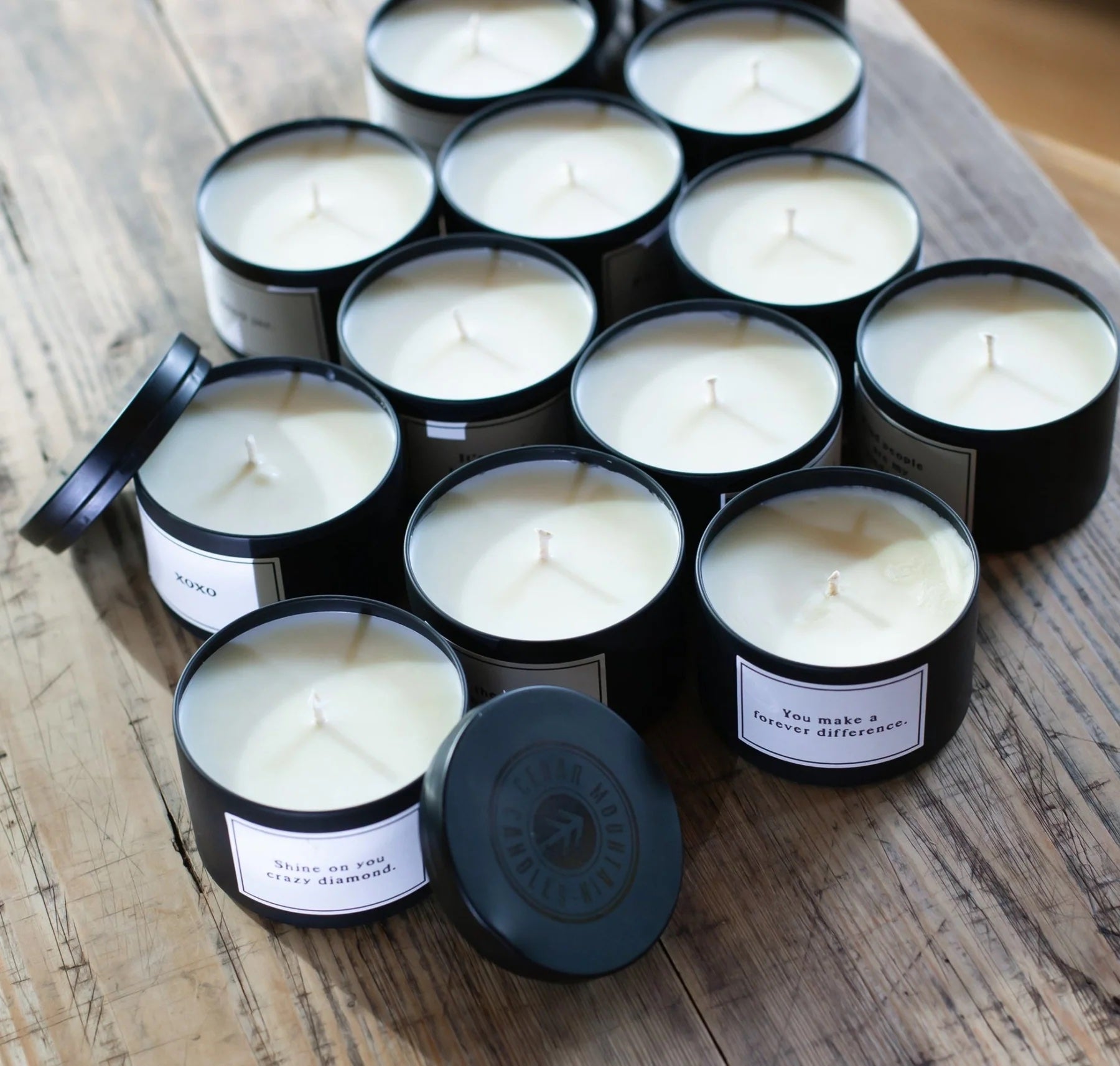 Black candles with labels on a wooden surface