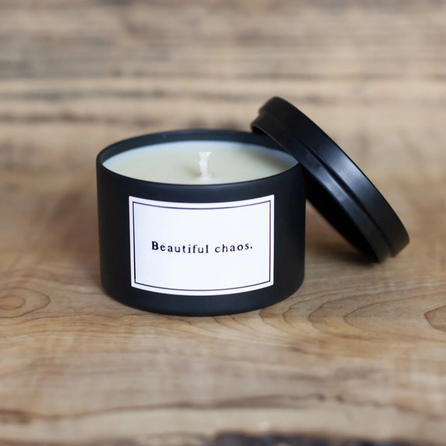 Black candle with a white label on a wooden surface