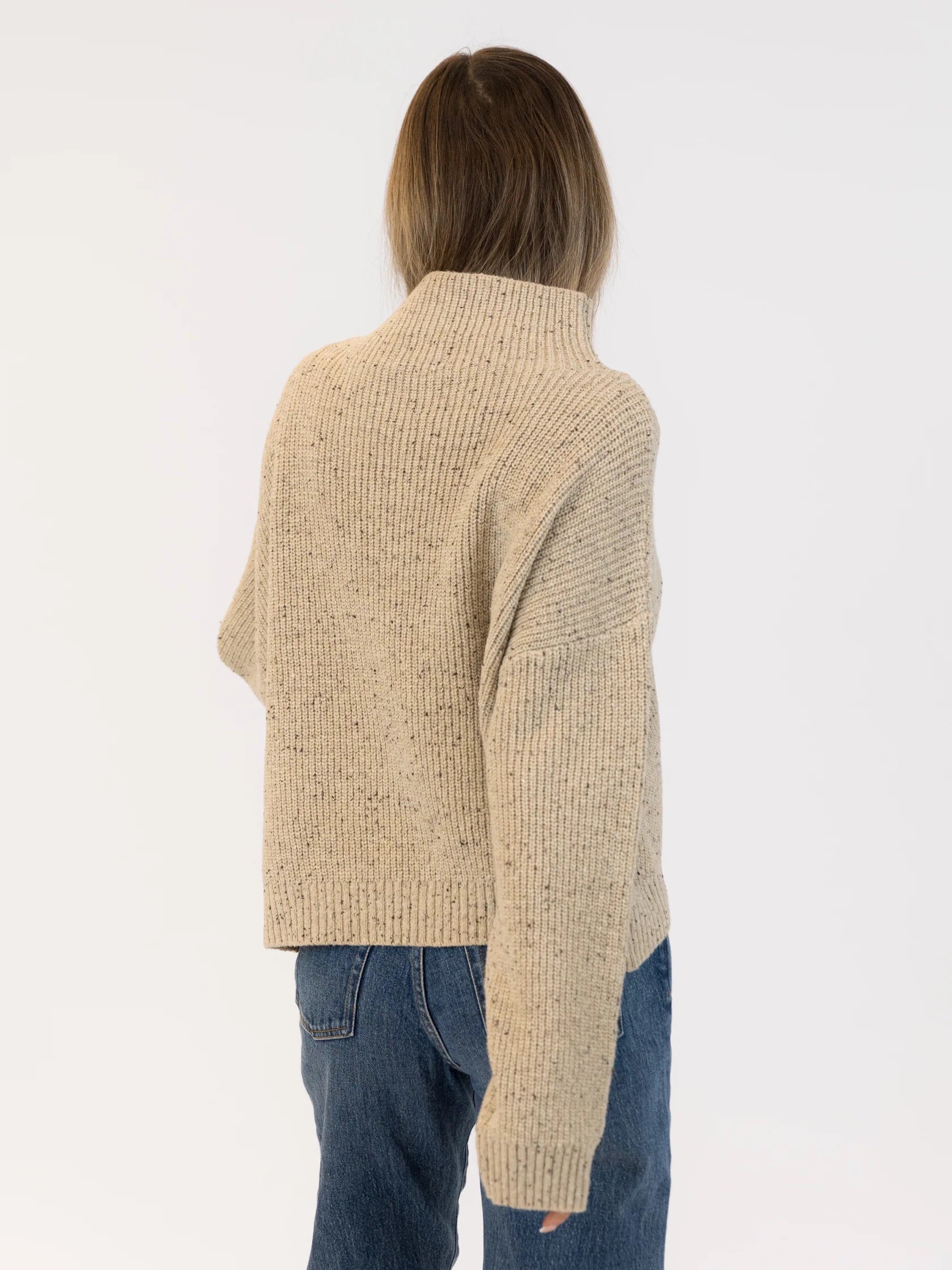 Person wearing a beige ribbed sweater and blue jeans on a white background | Lyla + Luxe Evolet Fleck Sweater | Neutral