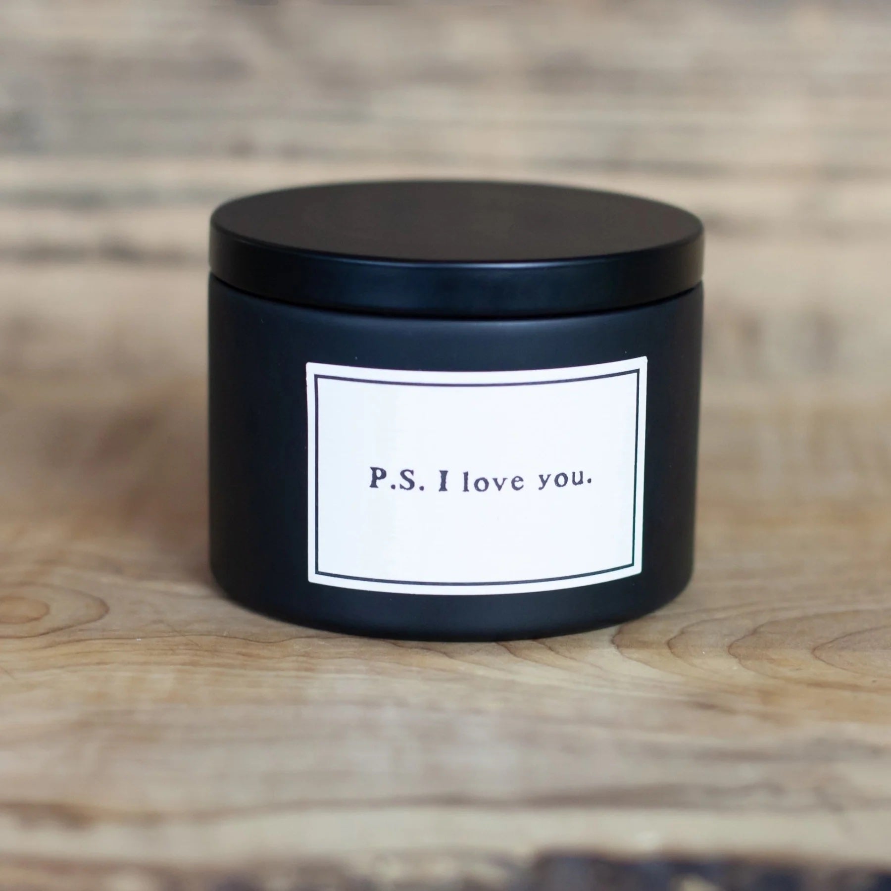 Black container with a white label reading 'P.S. I love you' on a wooden surface.